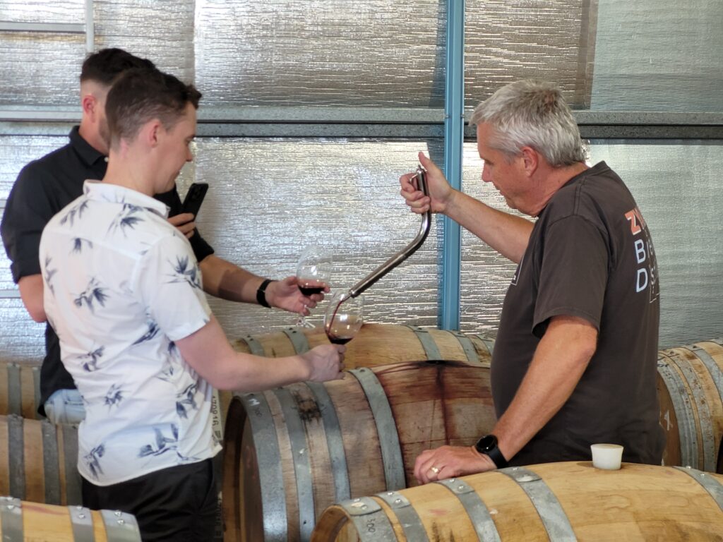 Using a wine thief to check the quality of the wine.